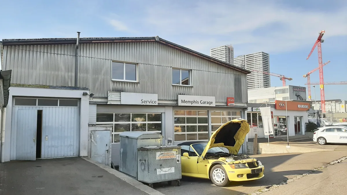 Aussenansicht eines flachen Gebäudes mit einer Autogarage im Untergeschoss. 